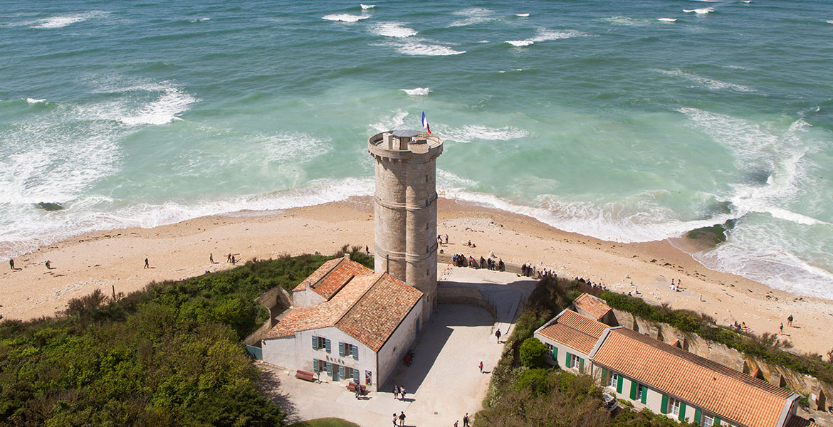 Phare des Baleines situé à Saint Clément des Baleines sur l'Île de Ré en Charente-Maritime avec la mer autour du Phare et de la végétation autour