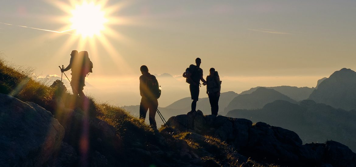 Des randonneurs sur une crête de montagne des Pyrénées Orientales au lever du soleil, avec des sommets et des vallées en arrière-plan.