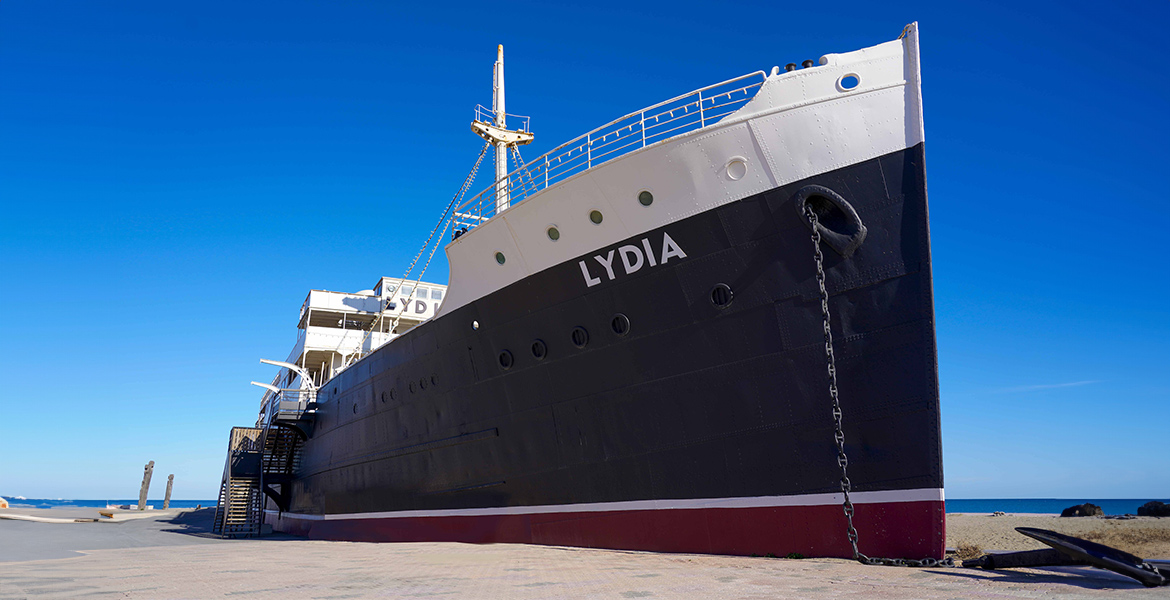 Le paquebot "Lydia", échoué sur la plage et transformé en attraction, sous un ciel bleu éclatant.