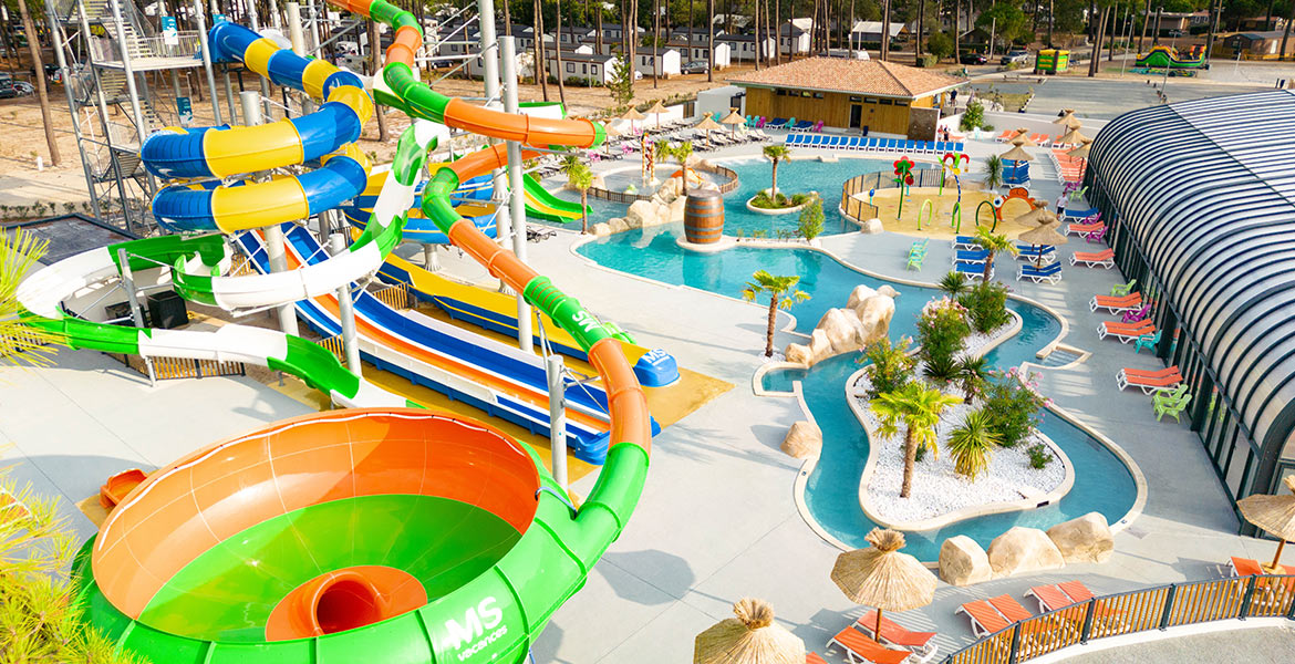 Complexe aquatique avec piscines extérieures, toboggans et espace détente avec des transats sous des parasols.