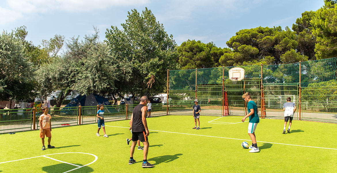 Plusieurs personnes jouent ensemble sur un terrain multisport du Camping Campéole La Côte des Roses à Narbonne Plage dans l'Aude