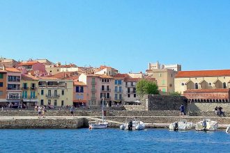 Vue du port de Collioure avec ses maisons colorées en arrière-plan et l'église Notre-Dame-des-Anges au bord de l'eau.