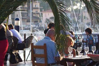 Personnes sur la terrasse d'un restaurant avec une vue sur un port