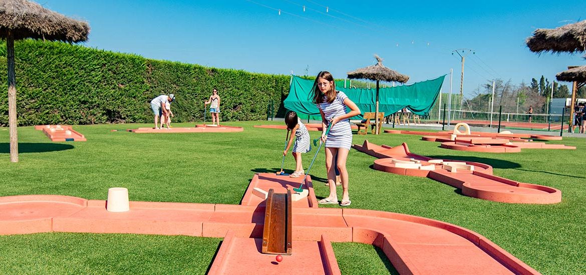 Une famille et des amis jouent au mini-golf au camping