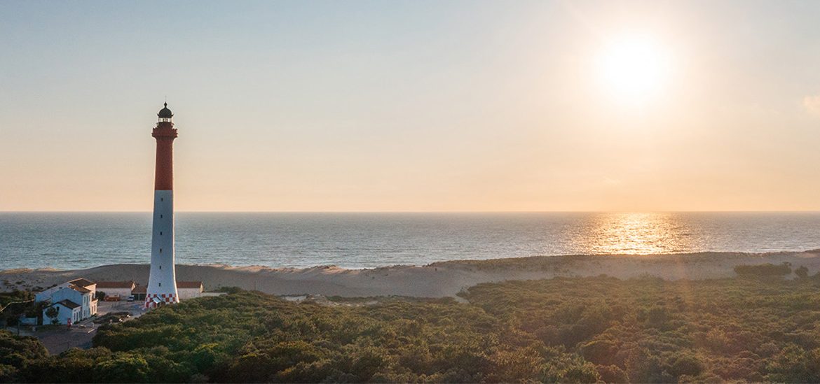 Plage de La Palmyre, Baie de Bonne Anse, en Charente Maritime sous un soleil couchant avec le Phare de la Coubre