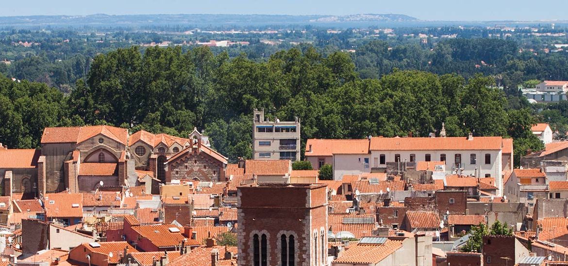 Vue aérienne de la vieille ville de Perpignan avec des toits en tuiles et le clocher d'une église.