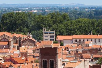 Vue aérienne de la vieille ville de Perpignan avec des toits en tuiles et le clocher d'une église.