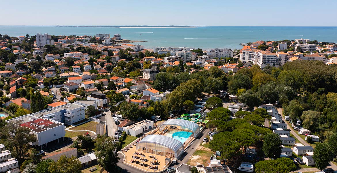 Vue aérienne du Camping Campéole Pontaillac Plage. Au premier plan, un complexe avec des piscines couvertes et des installations de loisirs est visible.