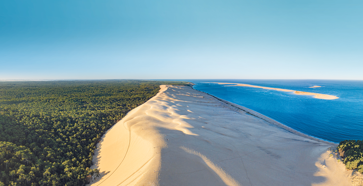 Photo aérienne de la dune du Pilat avec le banc d'Arguin et une forêt de pins.